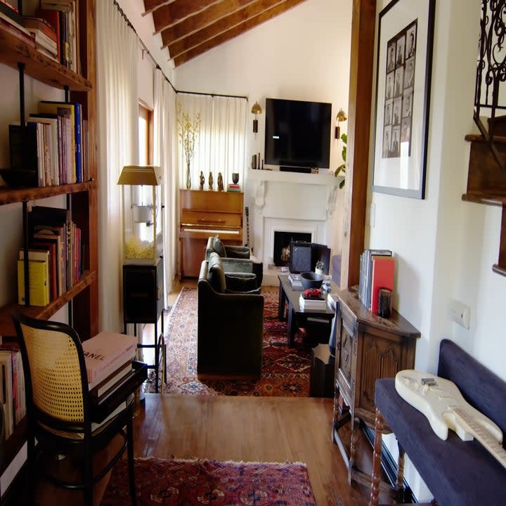 The living room is set up with a seating area, TV, and a book shelf