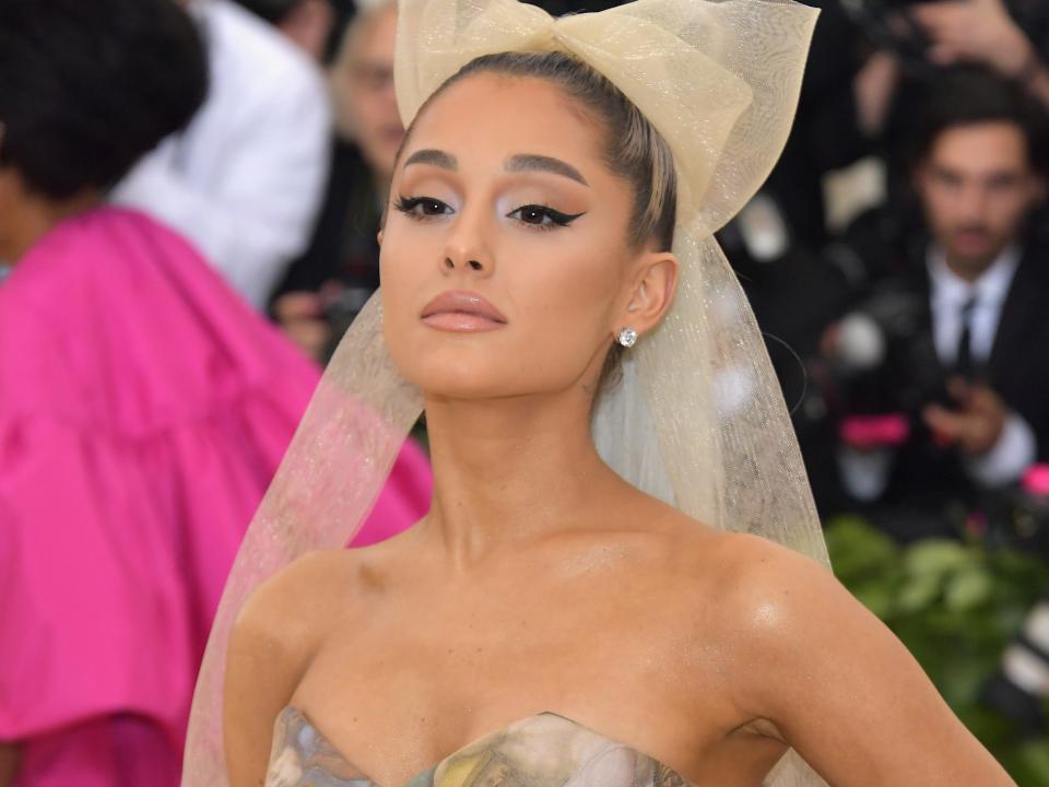 Ariana Grande in a beige dress with images of heavenly bodies