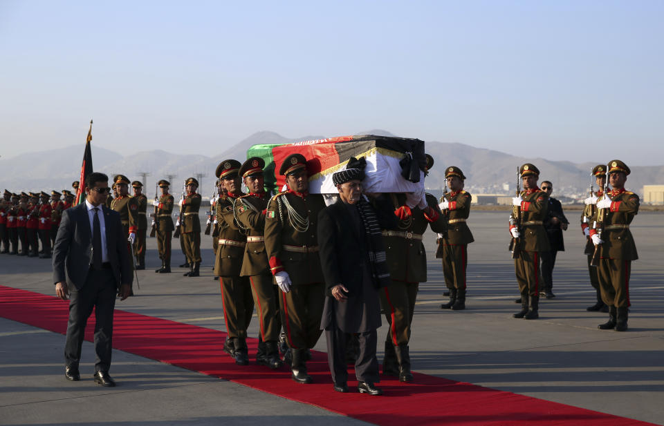 Afghan President Ashraf Ghani, foreground, and Afghan honor guards carry the coffin of Japanese physician Tetsu Nakamura during a ceremony before transporting his body to his homeland, at the Hamid Karzai International Airport in Kabul, Afghanistan, Saturday, Dec. 7, 2019. Nakamura was killed earlier this week in a roadside shooting in eastern Afghanistan. (AP Photo/Rahmat Gul)