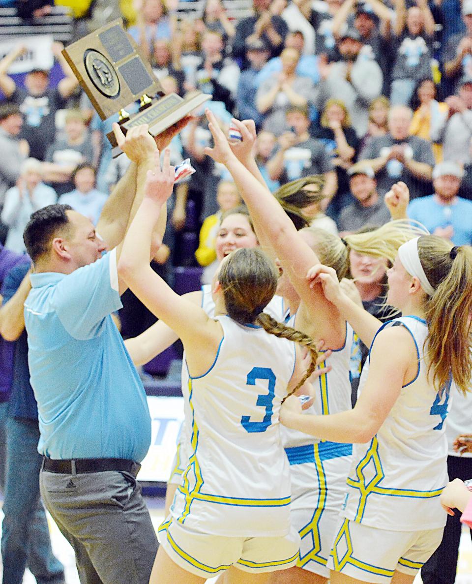 Head coach Tim Koisti brings the championship trophy to Hamlin High School's girls basketball players after they defeated Wagner 58-55 in the state Class A championship game on Saturday, March 11, 2023 in the Watertown Civic Arena.