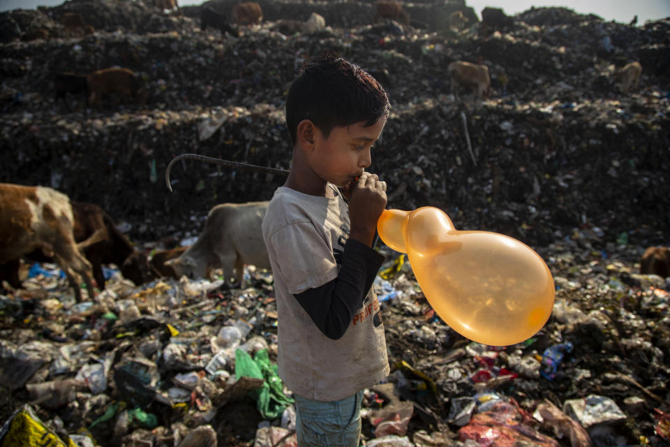 Imradul Ali, 10, blows a balloon which salvaged from a landfill on the outskirts of Gauhati, India, Thursday, Feb. 4, 2021. Once school is done for the day, Ali, rushes home to change out of his uniform so that he can start his job as a scavenger in India’s remote northeast. Coming from a family of scavengers or “rag pickers," Ali started doing it over a year ago to help his family make more money. Ali says he doesn’t want to spend his life doing this, but he doesn’t know what the future holds. (AP Photo/Anupam Nath)