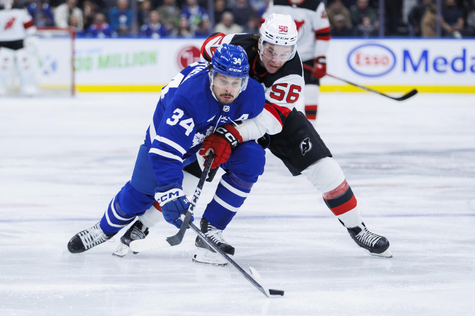 Toronto Maple Leafs center Auston Matthews (34) and New Jersey Devils left wing Erik Haula (56) battle for the puck during the first period of an NHL hockey game in Toronto on Tuesday, March 26, 2024. (Cole Burston/The Canadian Press via AP)