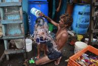 FILE - In this May 23, 2016, file photo, a man bath his son on a hot afternoon in a slum in Mumbai, India. For the third straight year, Earth set a record for the hottest year, NOAA and NASA announced. NASA says 2016 was warmer than 2015 - by a lot. It's mostly global warming with a little assist from the now-gone El Nino.(AP Photo/Rafiq Maqbool, File)