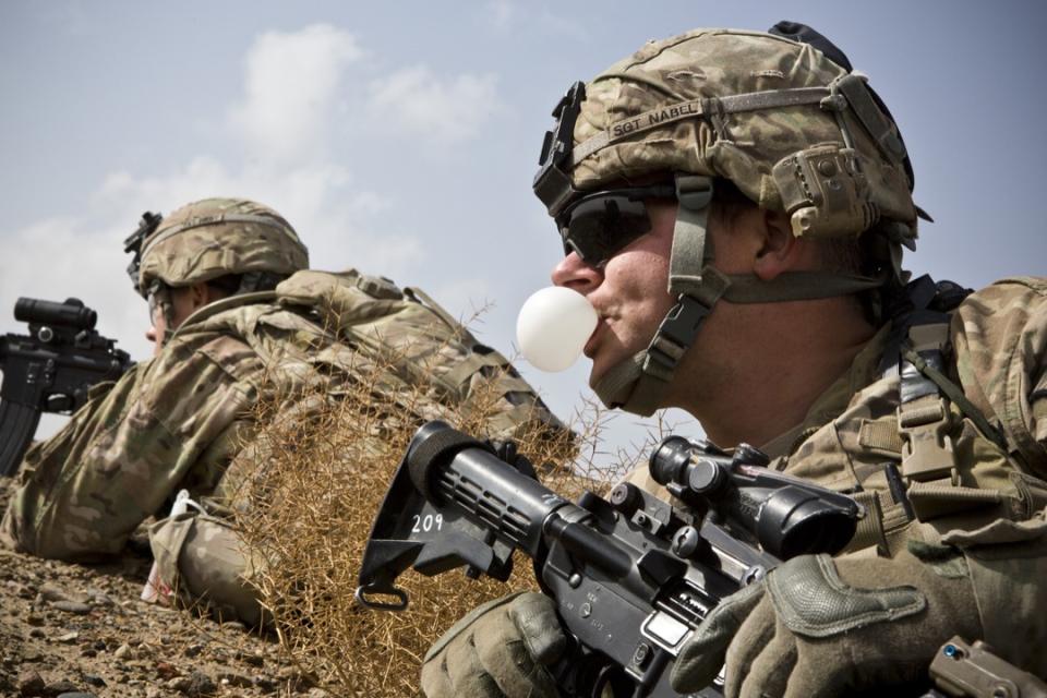 2013年2月3日，阿富汗南部坎大哈省，一名美軍士兵在哨站附近進行任務時嘴嚼吹波糖。