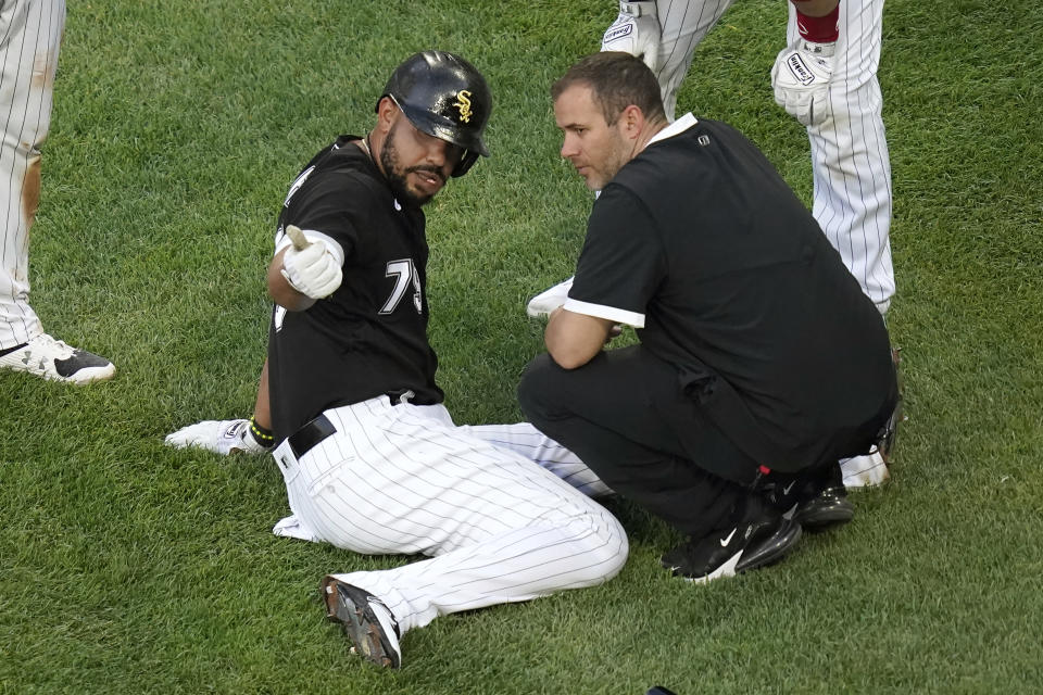 Chicago White Sox's Jose Abreu sits on the ground near home plate and talks with a member of the training staff, after Abreu ended up on the ground after Jake Lamb scored during the first inning of the team's baseball game against the Toronto Blue Jays on Wednesday, June 9, 2021, in Chicago. Abreu stayed in the game. (AP Photo/Charles Rex Arbogast)