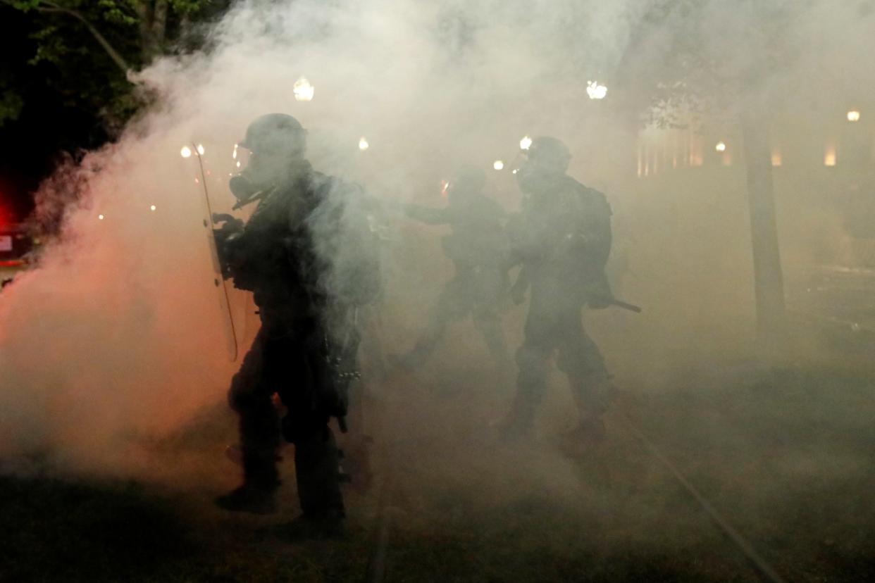 Law enforcement officers walk amidst tear gas during a protest following the police shooting of Jacob Blake: REUTERS