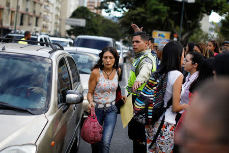 A police officer tries to control the traffic while people walk on the street during a blackout in Caracas, Venezuela February 6, 2018. REUTERS/Carlos Garcia Rawlins