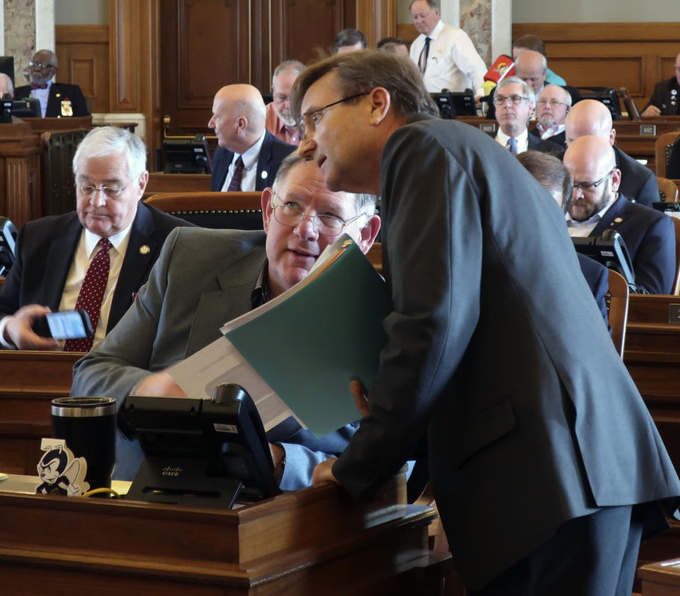 Kansas House Insurance Committee Chairman Jene Vickrey, right, R-Louisburg, confers with Majority Leader Dan Hawkins, R-Wichita, during a debate on an insurance bill sought by the Kansas Farm Bureau, Friday, April 5, 2019, at the Statehouse in Topeka, Kan. Lawmakers have approved the bill, which allows the Farm Bureau to sell health coverage to its members that doesn't comply with federal mandates. (AP Photo/John Hanna)