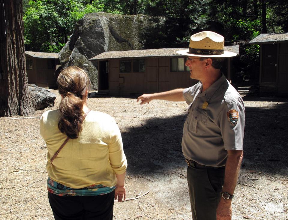 In this on Tuesday, June 12, 2012 photo, park spokesman Scott Gediman, right, speaks with Lisa Cesaro of the Delaware North Company, which operates the lodging and other concessions at Yosemite National Park. This portion of the family friendly Curry Village sits in an area that a new study says is at high risk of catastrophic rock falls. It was built in 1899 at the base of Glacier Point amid boulders from previous rock falls. One-third of the village's 600 cabins have been closed since a rock fall in 2008, and the study says a dozen others and several employee dormitories also must close. (AP Photo/Tracie Cone)