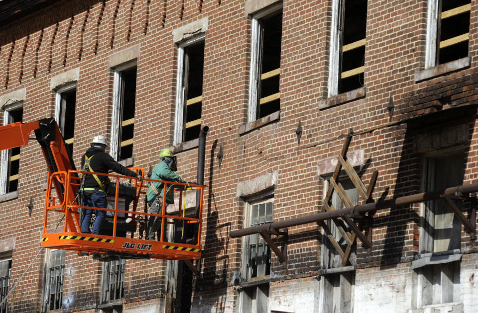 Construction crew members on a lift work on a once-abandoned cotton gin factory that is being renovated into apartments in Prattville, Ala., on Friday, Jan 28, 2022. The factory's history is tied up in slavery, and the project demonstrates the difficulty of telling complicated U.S. history. (AP Photo/Jay Reeves)