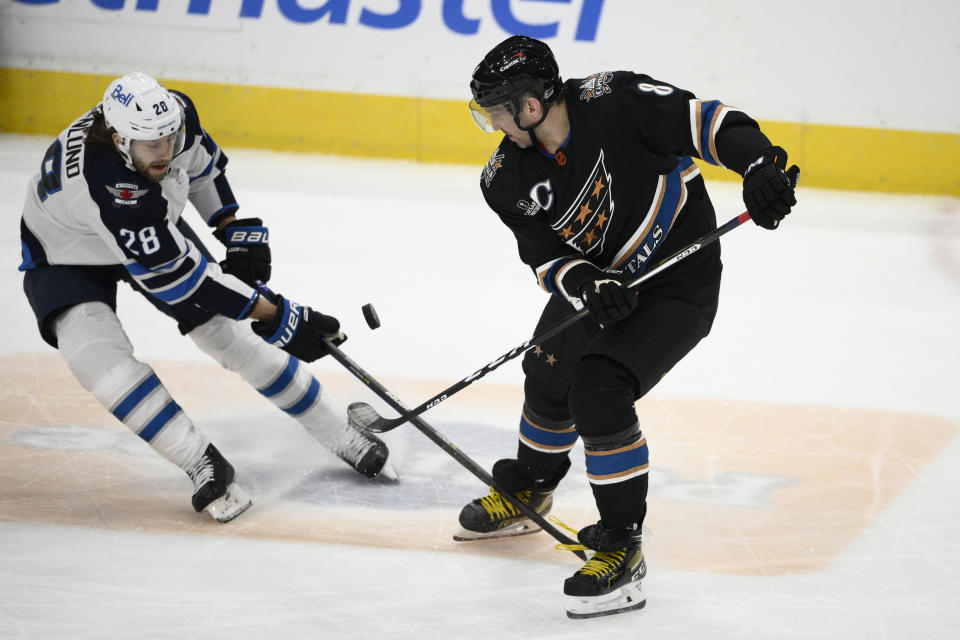 Washington Capitals left wing Alex Ovechkin (8) battles for the puck against Winnipeg Jets center Kevin Stenlund (28) during the first period of an NHL hockey game, Friday, Dec. 23, 2022, in Washington. (AP Photo/Nick Wass)