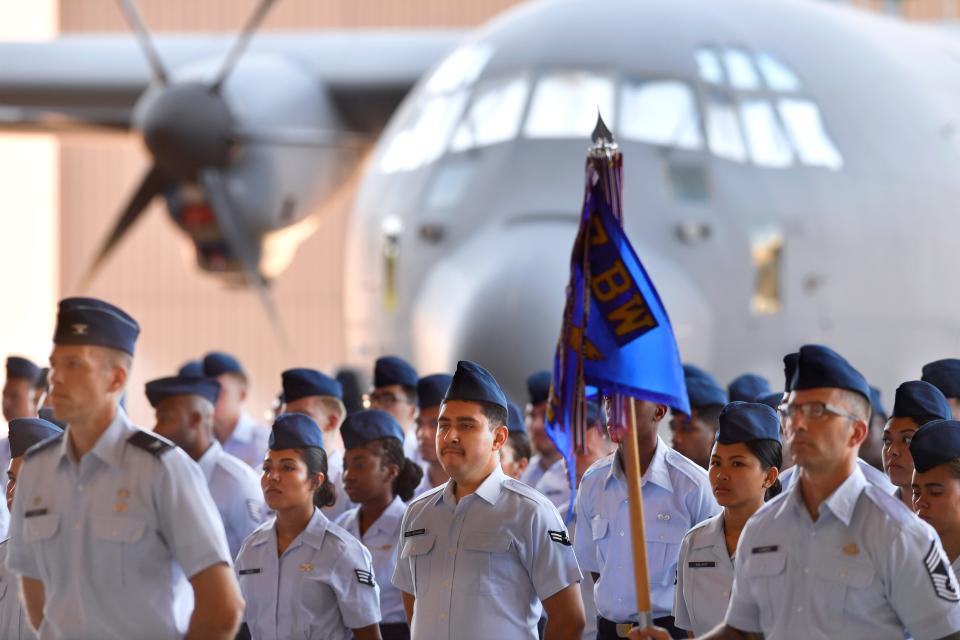 .S. Air Force personnel stand in formation with a C-130 in the background.