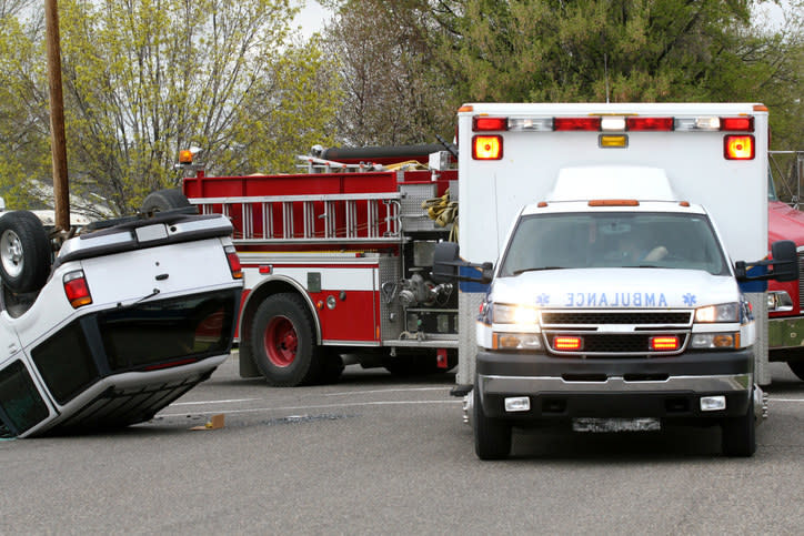 a car overturned and an ambulance and firetruck next to it