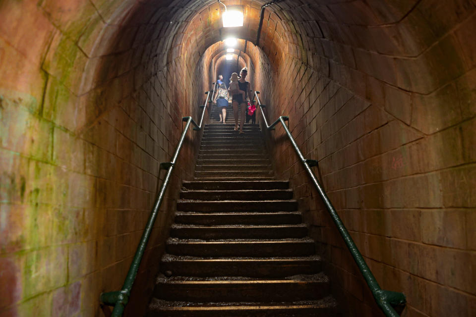 People walk down the steps of Smugglers tunnel that lead to Ness Cove beach in Shaldon, Devon, England, Thursday July 22, 2021. Visiting the fishing village of Shaldon a small cluster of mainly Georgian houses and shops at the mouth of the River Teign, is like stepping back into a bygone era. It features simple pleasures that hark back to analog, unplugged summer days: a book and a picnic blanket, a bucket and spade, fish and chips. (AP Photo/Tony Hicks)