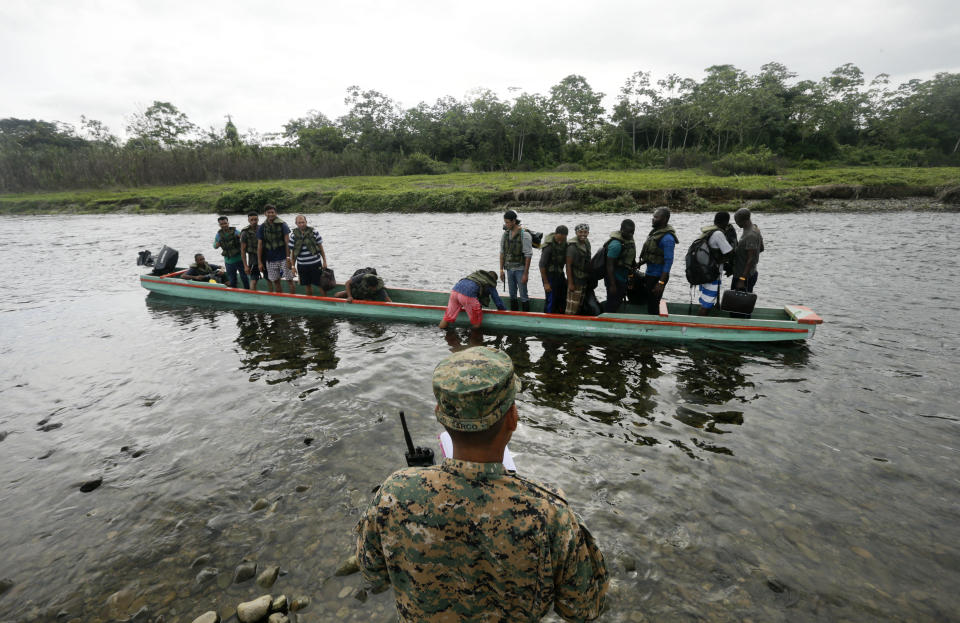 En esta imagen, tomada el 25 de mayo de 2019, un agente de policía cuenta los migrantes que se suben a una embarcación en la que recorrerán parte del Río Tuquesa hasta Peñitas, en Bajo Chiquito, en la provincia de Darién, Panamá. Según la policía fronteriza, al menos una docena de migrantes, probablemente más, murieron en recientes crecidas en ríos de Darién. (AP Foto/Arnulfo Franco)