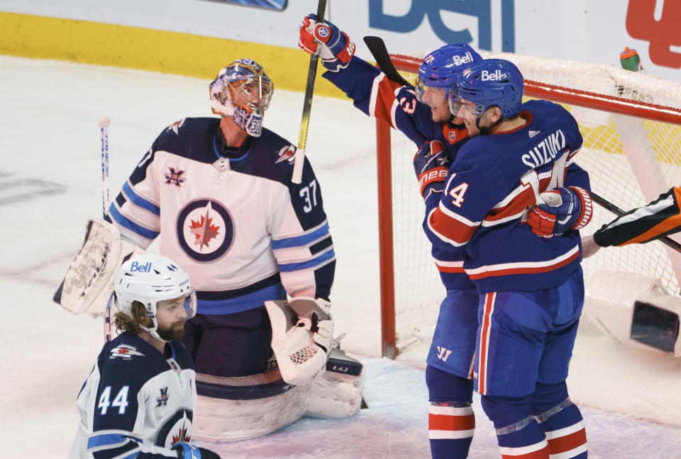 Montreal Canadiens' Tyler Toffoli, second from right, celebrates his goal past Winnipeg Jets goaltender Connor Hellebuyck (37) with teammate Nick Suzuki, right, during second-period NHL hockey game action in Montreal, Thursday, March 4, 2021. (Paul Chiasson/The Canadian Press via AP)