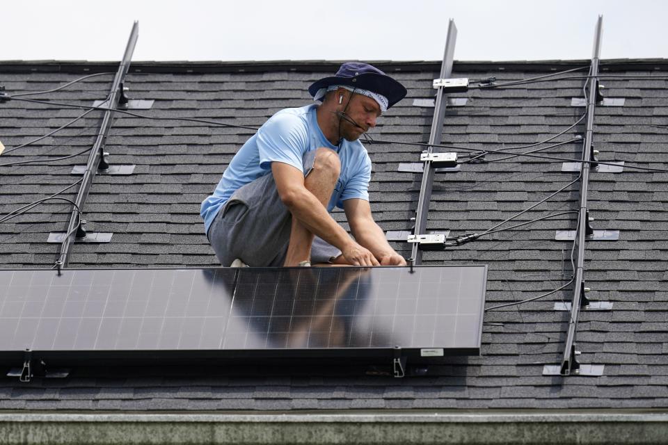 Brian Hoeppner connects a panel as he installs a solar array on the roof of a home in Frankfort, Ky., Monday, July 17, 2023. Since passage of the Inflation Reduction Act, it has boosted the U.S. transition to renewable energy, accelerated green domestic manufacturing, and made it more affordable for consumers to make climate-friendly purchases, such as installing solar panels on their roofs. (AP Photo/Michael Conroy)
