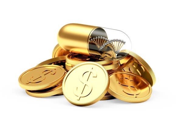 A golden capsule resting atop a pile of gold coins.
