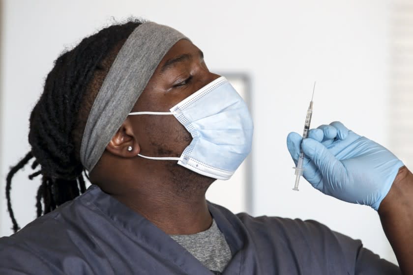 Los Angeles, CA - April 09: Medical assistant Adrian Davis checks for air-bubbles in a syringe before giving a COVID-19 vaccine to client at a vaccination clinic established by Councilman Curren Price in partnership with St. John's Well Child and Family Center at St. Patrick's Catholic Church on Friday, April 9, 2021 in Los Angeles, CA.(Irfan Khan / Los Angeles Times)