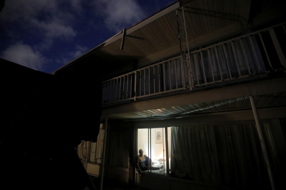 Tasha Whitt sits by a window in her room at the damaged American Quality Lodge where she continues to live in the aftermath of Hurricane Michael, in Panama City, Fla., Tuesday, Oct. 16, 2018. Whitt, who broke her foot during the storm, worries about looters at night who residents say have taken money, jewelry, food and even rain-soaked clothes from rooms ripped apart and left open to the elements by Michael. (AP Photo/David Goldman)