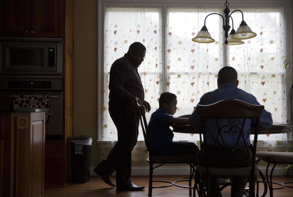 Shelton Stroman, left, and partner Christopher Inniss, right, help their son Jonathan, 9, with homework in the couple's kitchen, Thursday, April 17, 2014, in Snellville, Ga. A gay rights group on Tuesday, April 22, 2014, filed a federal lawsuit in Atlanta challenging the state of Georgia’s constitutional ban on same-sex marriages. (AP Photo/David Goldman)