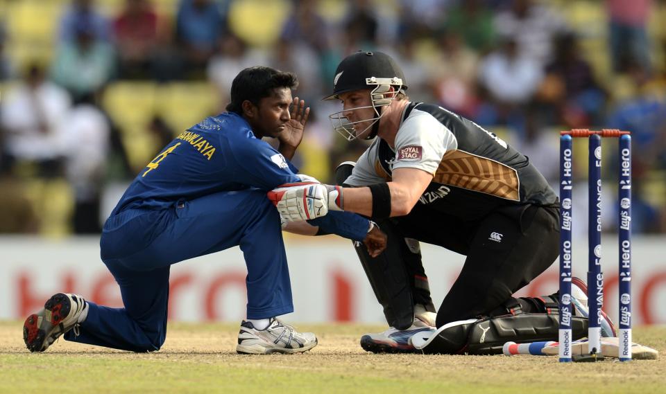 Sri Lanka's Akila Dhananjaya is helped by New Zealand's Brendon McCullum (R) after being hit in the face by the ball during the Twenty20 World Cup Super 8 match at Pallekele in Sri Lanka September 27, 2012. REUTERS/Philip Brown (SRI LANKA - Tags: SPORT CRICKET)