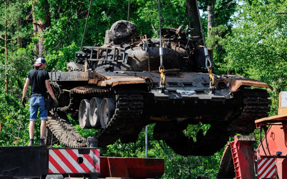A worker seen loading a destroyed military tank of the Russian army onto a towing vehicle at Dmytrivka village near the Ukrainian capital Kyiv - Sergei Chuzavkov/SOPA Images