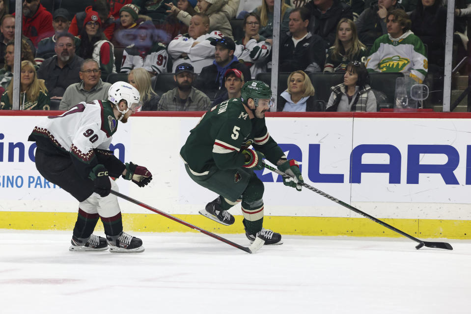 Minnesota Wild defenseman Jake Middleton (5) controls the puck against Arizona Coyotes defenseman J.J. Moser (90) during the first period of an NHL hockey game Sunday, Nov. 27, 2022, in St. Paul, Minn. (AP Photo/Stacy Bengs)