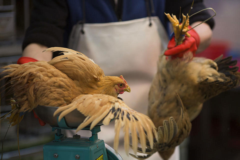 A vendor weighs chickens at a market. Source: Getty