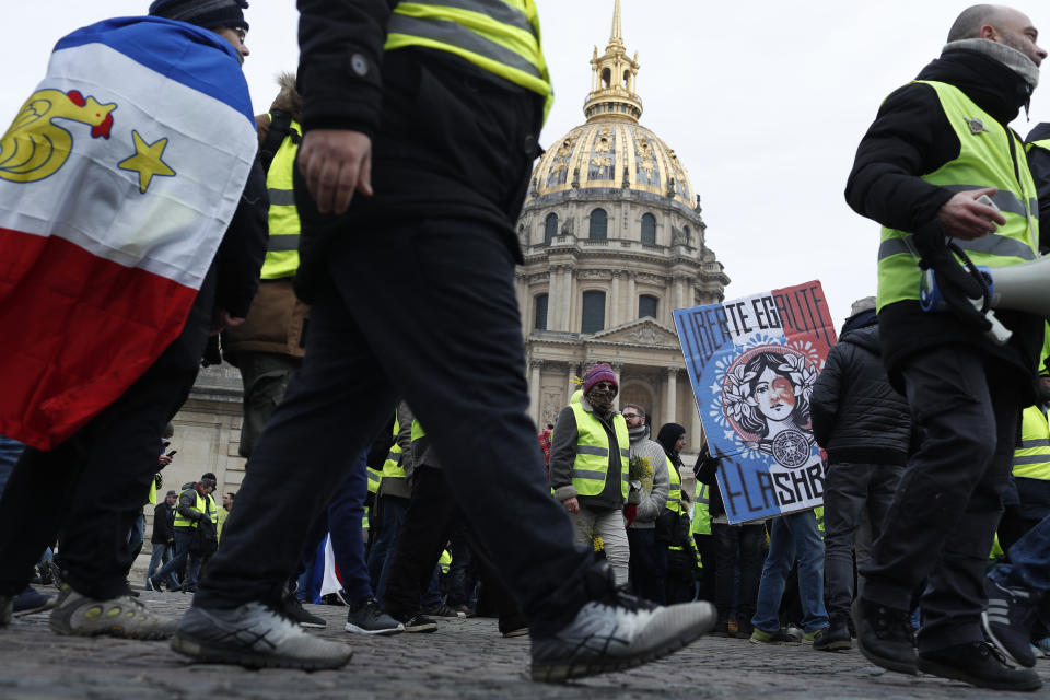 Yellow vest protesters march past the Invalides monument Saturday, Jan. 19, 2019 in Paris. Hundreds of yellow vest protesters rallied in several French cities for a tenth consecutive weekend on Saturday despite a national debate launched this week by President Emmanuel Macron aimed at assuaging their anger. (AP Photo/Thibault Camus)