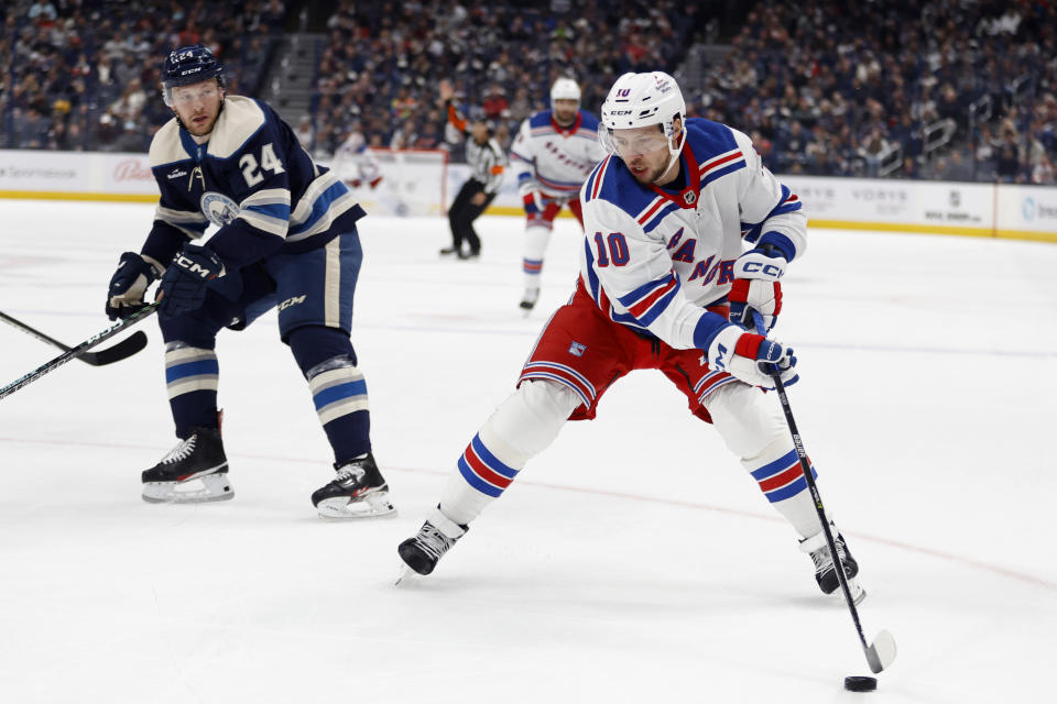 New York Rangers forward Artemi Panarin, right, controls the puck in front of Columbus Blue Jackets forward Mathieu Olivier during the first period of an NHL hockey game in Columbus, Ohio, Saturday, Oct. 14, 2023. (AP Photo/Paul Vernon)