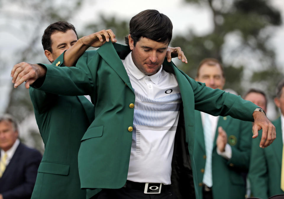 Defending Masters' champion Adam Scott, of Australia, helps Bubba Watson, right, with his green jacket after winning the Masters golf tournament Sunday, April 13, 2014, in Augusta, Ga. (AP Photo/David J. Phillip)