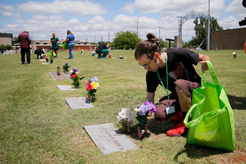 Brent Purinton, with Daily Living Centers, places flower arrangements on graves Thursday at Veterans Cemetery in Oklahoma City. Seniors and developmentally disabled adults from Daily Living Centers repurposed flowers from Dignity Memorial to place them on graves at Veterans Cemetery with help from local students.