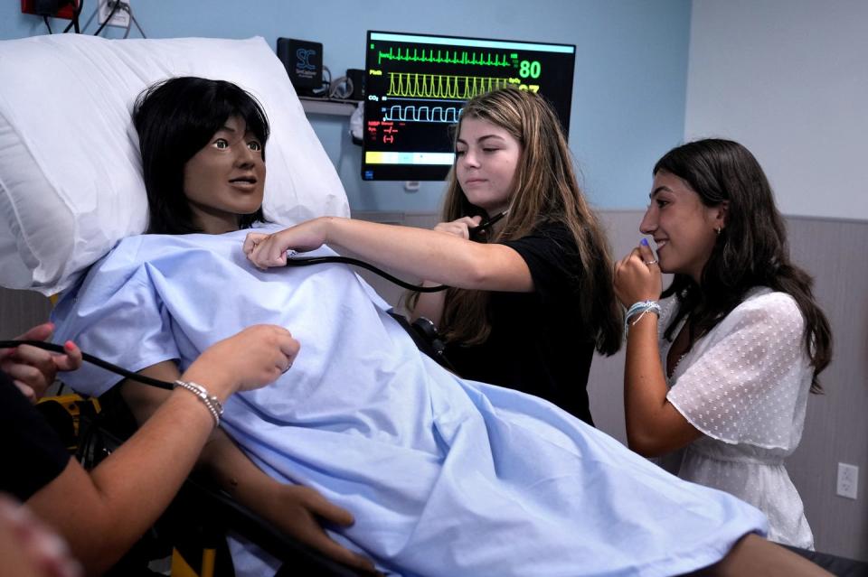 La Salle Academy student Isabella Tofani of Cranston listens for a heartbeat from a simulation manikin as fellow La Salle student Brianna Pires of Pawtucket watches. The two were part of a student tour of the new Providence College Department of Nursing and Health Sciences on Monday morning.