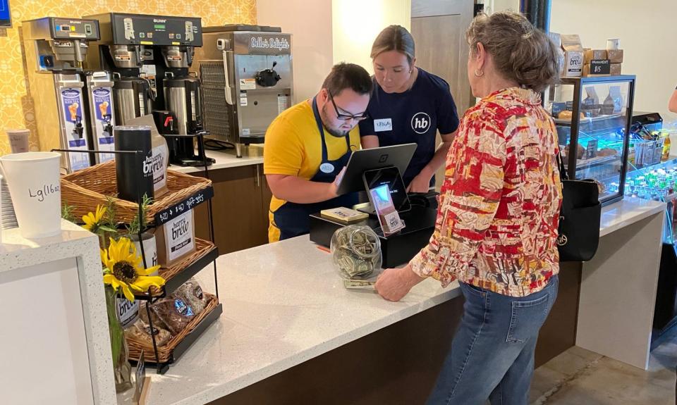 Alexander Hunt, a Happy Brew barista, takes a customer's order as Christy Iglesias, a coffee shop board member, looks on during the Dec. 9, 2023, grand opening of the cafe at 3200 Hendricks Ave. in historic San Marco.