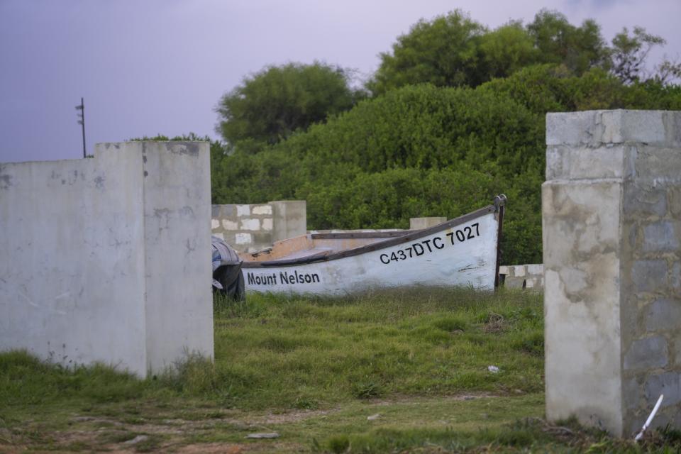 A fishing boat rests in a courtyard in the seaside village of Hawston, South Africa, April 27, 2023. Nearly every house in Hawston has a boat in its yard, sometimes two. It takes a moment to realize many are out of action, grass sprouting through holes in hulls that haven't touched water for years. They are relics of another time, when people fished for their livelihood and the ocean provided more than enough. (AP Photo/Jerome Delay)