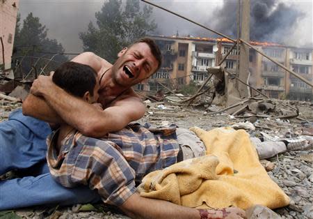 A Georgian man cries as he holds the body of his relative after a bombardment in Gori, 80 km (50 miles) from Tbilisi, in this August 9, 2008 file photo. REUTERS/Gleb Garanich/Files