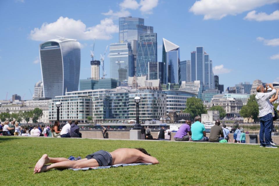 People enjoy the hot weather with a view of the City of London.  (Lucy North/PA) (PA Archive)