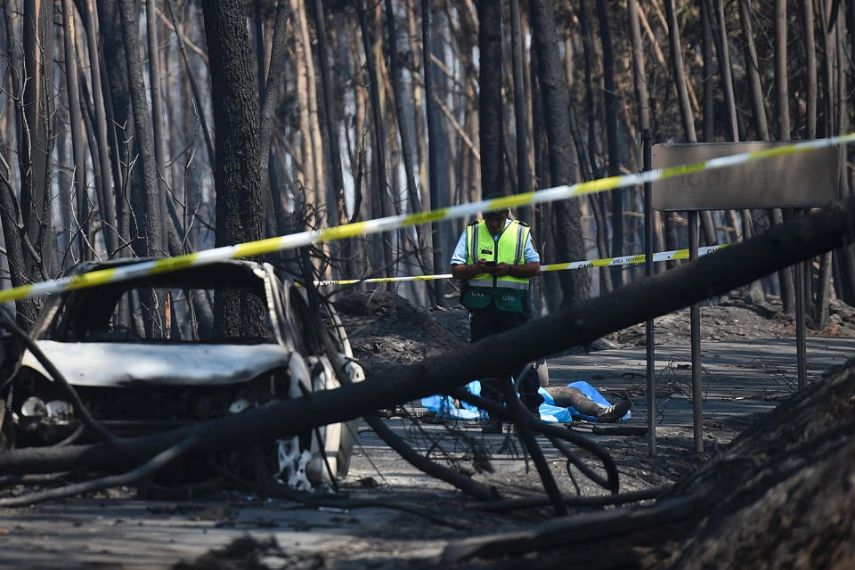 <p>A policeman stands near two burned out cars and the body of a victim of a wildfire in a forest of Figueiro dos Vinhos, Portugal, June 18, 2017. (Patricia De Melo Moreira/AFP/Getty Images) </p>