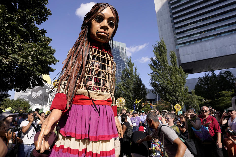 Little Amal, a 12-foot puppet of a 10-year-old Syrian refugee girl, is followed by a crowd while walking with the assistance of puppeteers, Thursday, Sept. 7, 2023, in Boston. The puppet is scheduled to journey across the United States, with planned stops in over 35 towns and cities, between Sept. 7 and Nov. 5, 2023, in an effort to raise awareness about refugees and displaced people across the world. (AP Photo/Steven Senne)