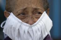 With tears on her eyes and wearing a home made face mask, a devotee of the "Nazareno de San Pablo" watches a statue of Jesus transported in a Pope mobile during Holy Week celebrations in Caracas, Venezuela, Wednesday, April 8, 2020. The annual procession, in which pilgrims normally take to the streets, is not allowed this year due to quarantine laws to help contain the spread of the new coronavirus, so the Catholic Church is driving the religious icon around the capital for people to see from their homes. (AP Photo/Ariana Cubillos)