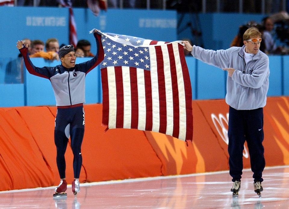 USA’s Derek Parra and coach Bart Schouten hold the American flag between them after Parra set a world record to win the gold medal in the 1,500 meter speedskating event on Tuesday, Feb. 19, 2002. | Scott G Winterton, Deseret News