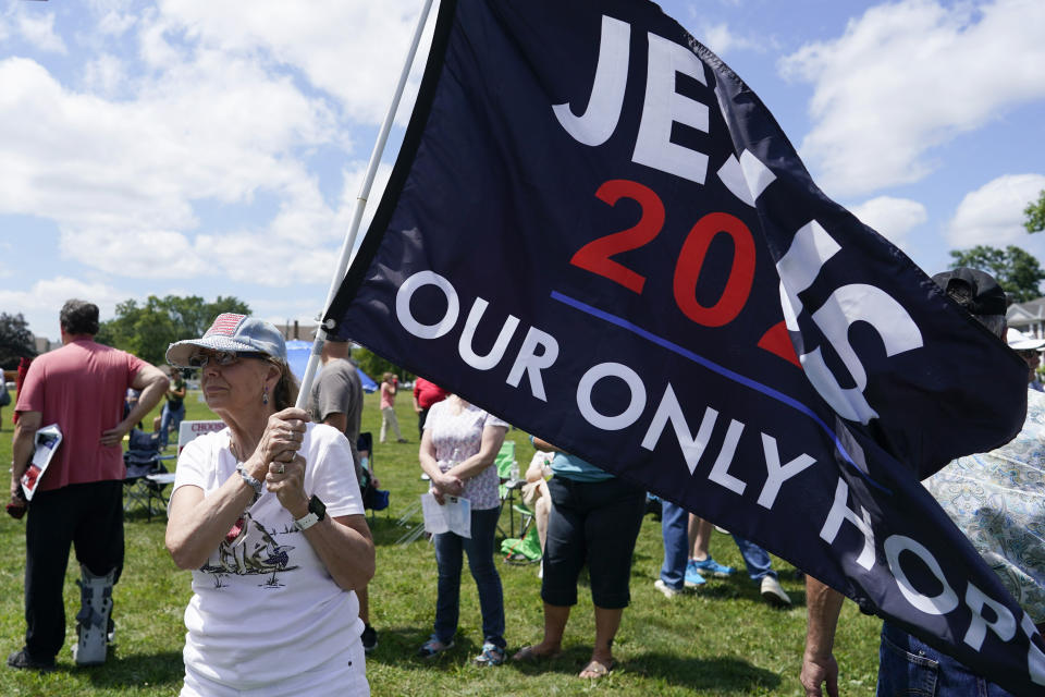 Jen Lanham holds a flag before the start of a "rosary rally" on Sunday, Aug. 6, 2023, in Norwood, Ohio. A national religious organization, Catholics for Catholics, gathered a lineup of anti-abortion influencers and conspiracy theorists from across the U.S. to speak at the rally to urge a “yes” vote on a ballot question in Ohio, known as Issue 1. If voters approve Issue 1, it would make it more difficult for an abortion rights amendment on the November ballot to succeed. (AP Photo/Darron Cummings)