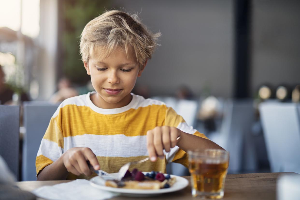 Little boy having crepes for breakfast. The crepes are sprinkled with fruits - blueberries and raspberriesNikon D850