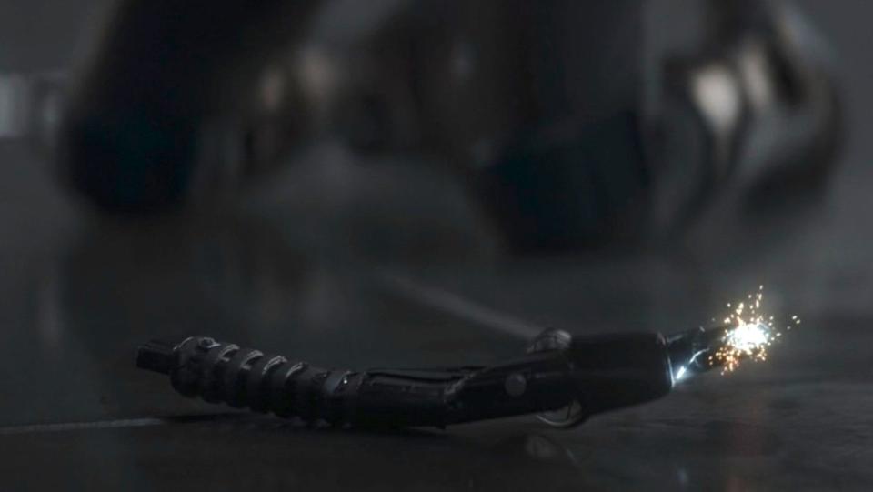 The crushed Darksaber crackles with light on the Mandalorian