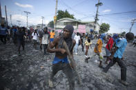 A protester carries a piece of wood simulating a weapon during a protest demanding the resignation of Prime Minister Ariel Henry, in the Petion-Ville area of Port-au-Prince, Haiti, Monday, Oct. 3, 2022. (AP Photo/Odelyn Joseph)