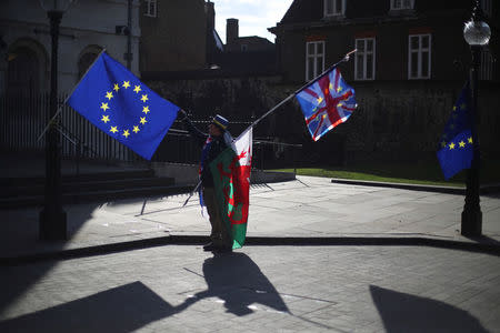 An anti-Brexit demonstrator waves EU, Union and Welsh flags opposite the Houses of Parliament in London, Britain, March 19, 2018. REUTERS/Hannah McKay