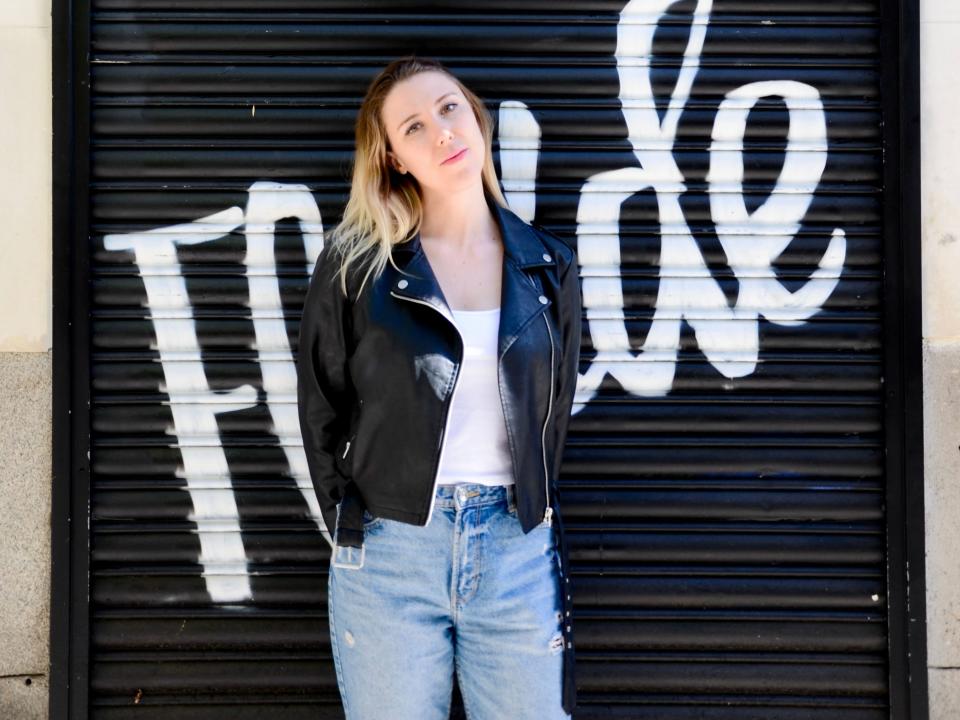 Olivia Blase in a leather jacket standing in front of a black wall