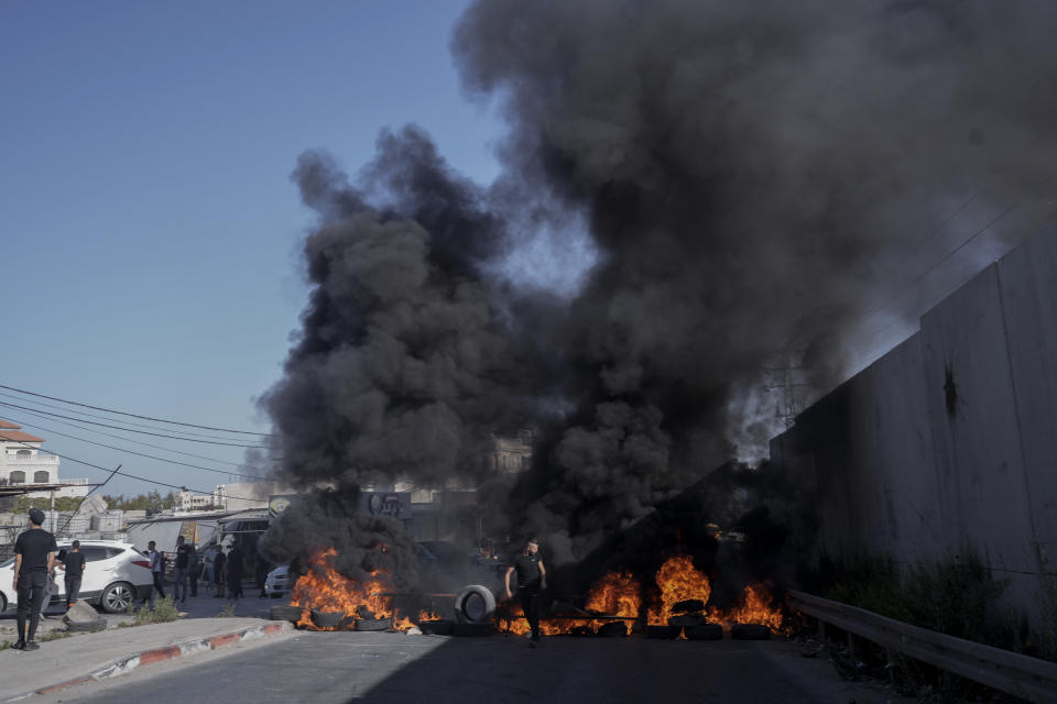 Tires set fire by Palestinians burn at the site where two Palestinians were shot and killed by the Israeli army in the Jalazone refugee camp near the city of Ramallah, West Bank, Monday, Oct. 3, 2022. Palestinian officials say the Israeli military has killed two Palestinians in the occupied West Bank. The Israeli military says it was on an arrest raid early Monday and alleges the two suspects tried to ram their car into soldiers, a claim that could not be independently verified. (AP Photo/Majdi Mohammed)