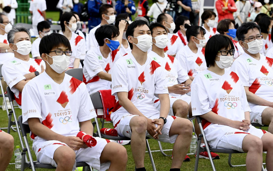Olympic torchbearers wearing face masks sit and wait for their turn in Kanazawa, central Japan, Monday, May 31, 2021. Japan, seriously behind in coronavirus vaccination efforts, is scrambling to boost daily shots as the start of the Olympics in July closes in. (Kazushi Kurihara/Kyodo News via AP)